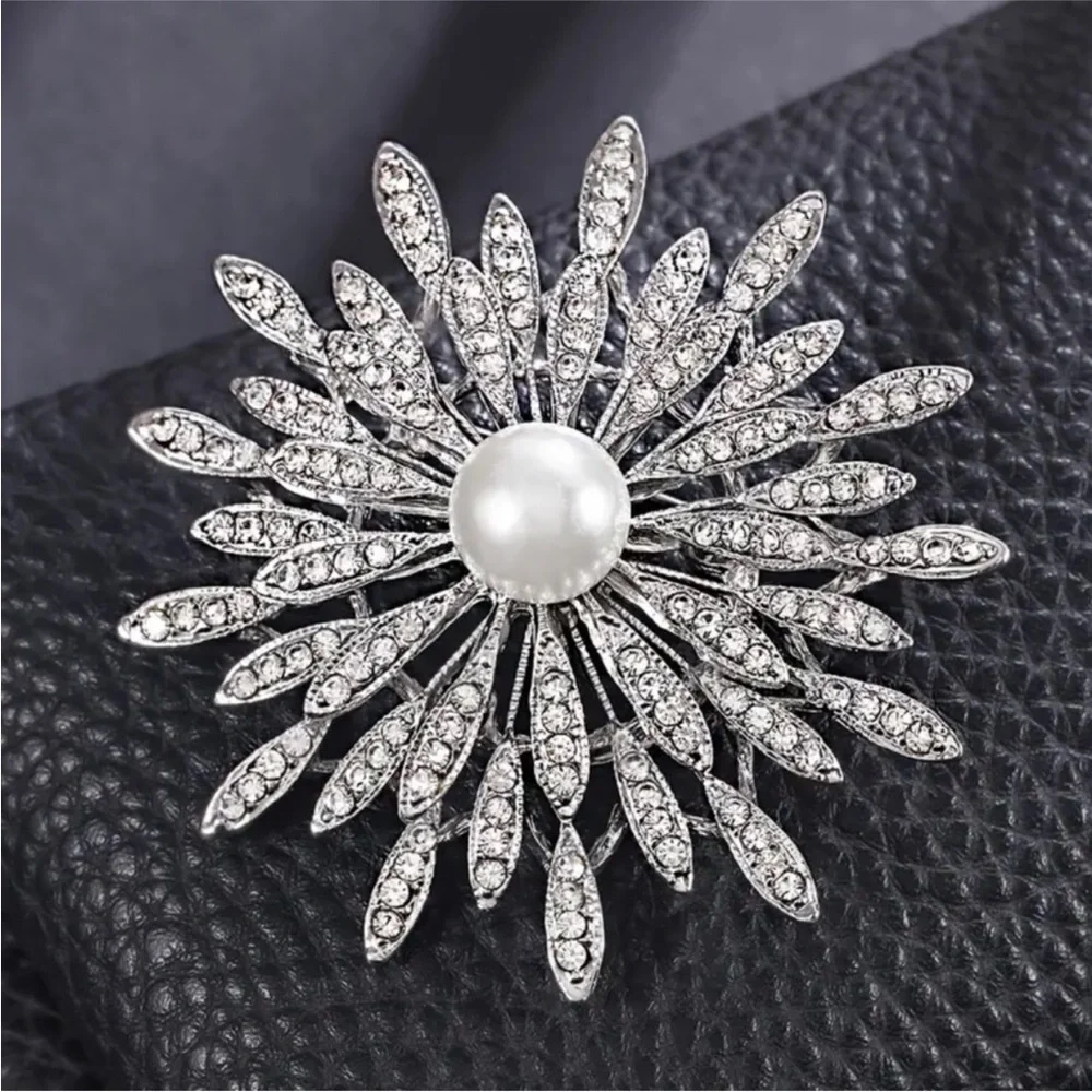 New silver-toned sunburst brooch clear rhinestones and a central faux pearl